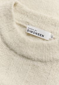 Sweter dzianinowy w kolorze kremowym o miękkiej teksturze, okrągłym dekolcie oraz metce z napisem "KAREN BY SIMONSEN" w rozmiarze M. Widoczne detale w wzorze.