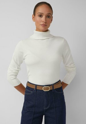 White knitted turtleneck sweater with ribbed cuffs, paired with high-waisted dark blue jeans and a light brown belt featuring a gold buckle.