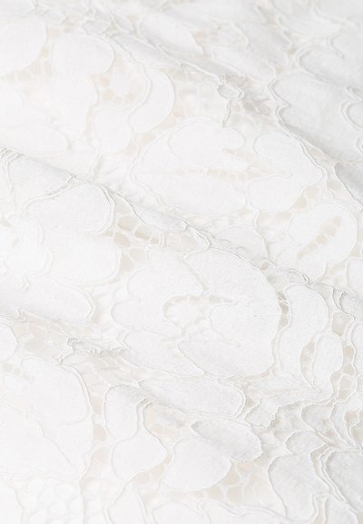 Λευκό δαντελωτό ύφασμα με λουλουδάτο σχέδιο, που διαθέτει περίπλοκη υφή και διάφανεις τμήματα, δημιουργώντας μια στρωτή εμφάνιση.