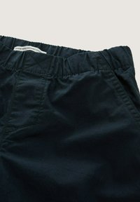 Marineblauwe elastische broek gemaakt van biologisch katoen, met een gladde textuur, subtiele glans en een eenvoudig ontwerp met zijzakken.