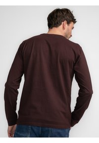 Koszula z długim rękawem, okrągłym dekoltem w ciemnym burgundzie, wykonana z bawełny, charakteryzująca się gładką fakturą i prostym wzornictwem bez widocznych grafik.