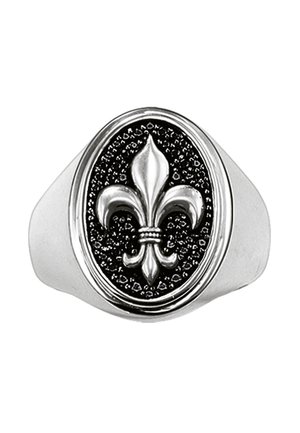 Silberner Siegelring mit erhabenem Fleur-de-Lis-Symbol auf einem strukturierten schwarzen ovalen Hintergrund.