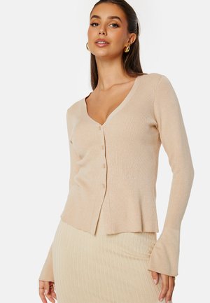 Beige ribbed cardigan featuring a V-neck, five buttons, and long sleeves with flared cuffs, made from a soft knit fabric.
