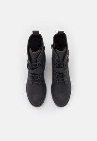 Černé kotníkové boty vyrobené z hladké kůže, s šněrováním, bočním zipem a zpevněnou špičkou. Plochá podrážka s texturovanými detaily.