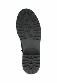 Suela de zapato de goma negra con un diseño texturizado, que presenta formas concéntricas y patrones en zigzag. Incluye el logotipo de la marca y la talla marcada como 37.