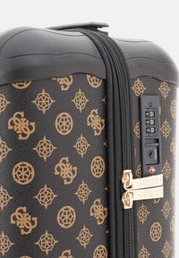 Black patterned hard-shell suitcase with gold logo accents, dual zippers, and a combination lock on the side for security.