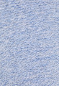 Tissu tricoté bleu clair texturé avec un motif marbré subtil, présentant des variations de teinte et une surface douce et lisse.