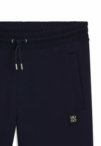 Pantalones de chándal azul marino con cintura elástica y cordón ajustable, que cuentan con un bolsillo lateral y un pequeño parche con el logo "HUGO".