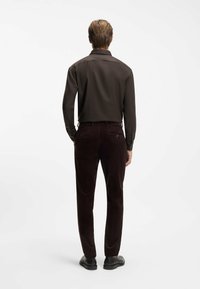 Brun langærmet skjorte parret med mørk burgunder corduroypants. Har en lige pasform, tekstureret stof og klassisk baglomme design.