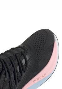 Svart sportskor med övre del av mesh och syntetmaterial, med en rosa mellansole och texturerad sula. Lightstrike-logotyp på sidan.