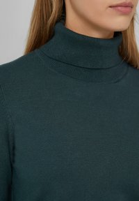 Türkiser Rollkragenpullover aus weich gestricktem Material. Verfügt über einen gerippten Kragen und eine glatte Textur, die eine figurbetonte Silhouette schafft.
