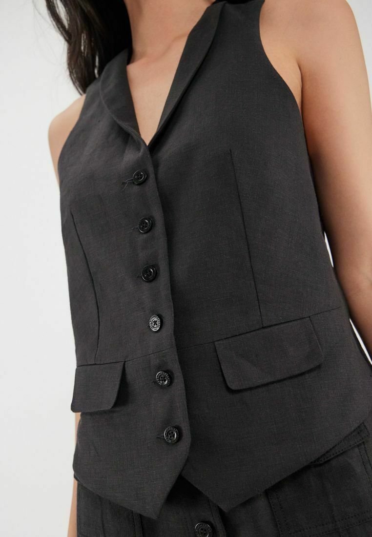 Gilet sans manches en lin noir avec six boutons frontaux, revers en pointe et deux poches avant. Texture lisse avec une coupe ajustée.