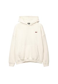 Helle Kapuzenjacke in Cremefarbe mit vorderer Kängurutasche und kleinem roten gestickten Logo auf der linken Brust, keine sichtbaren Zugbänder.