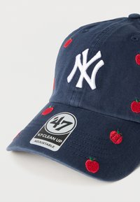 Καπέλο ρυθμιζόμενο σε ναυτικό μπλε χρώμα με κεντητό λευκό λογότυπο και κόκκινες σχεδιάσεις μήλων στο ύφασμα. Διαθέτει καμπυλωτή γείσο και ετικέτα μάρκας στο πλάι.