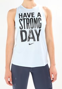Top deportivo sin mangas de color azul claro con texto grande en negro: "TEN UN DÍA FUERTE," con un logo de Nike en la parte inferior.