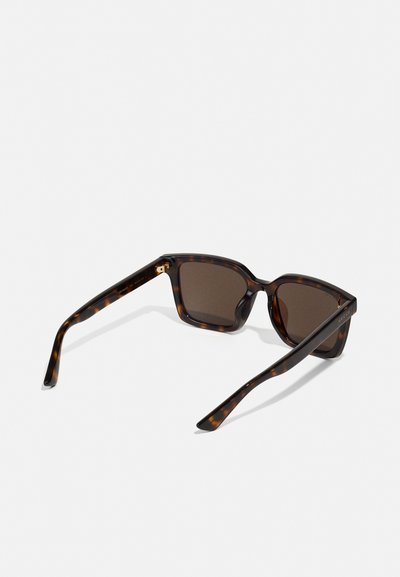 Tortoiseshell zonnebril met bruine lenzen, hoekige montuur en slanke pootjes. Heeft gouden hardware op de scharnier.