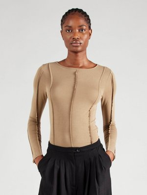 Beige top met lange mouwen, een aansluitend ontwerp, accentueerde naden en een ronde halslijn. Gecombineerd met zwart geplooide broek met hoge taille.