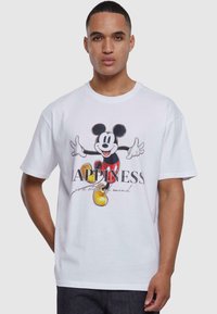 Hvit bomull t-skjorte med et trykt grafisk motiv av Mickey Mouse og teksten "LYKKE er en tilstand av sinn" i svart og gult.
