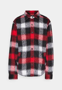 Langærmet skjorte med knapper, med tern i rødt, sort og hvidt samt to brystlommer, vist på en hvid baggrund.