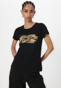 T-shirt nera in cotone con design di stampa animale dorata sul petto, caratterizzata da una vestibilità rilassata e maniche corte. Nessuna etichetta visibile.
