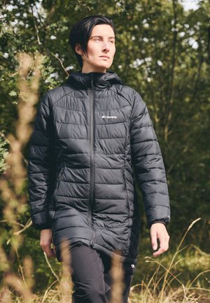 Chaqueta acolchada negra con cuello alto, cierre de cremallera y bolsillos laterales. Presenta un patrón de costuras y logo en el pecho.