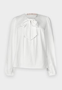 Blusa bianca con scollo rotondo, fiocco al collo e dettagli smock sul giogo. Maniche lunghe e arricciate con polsini elasticizzati.