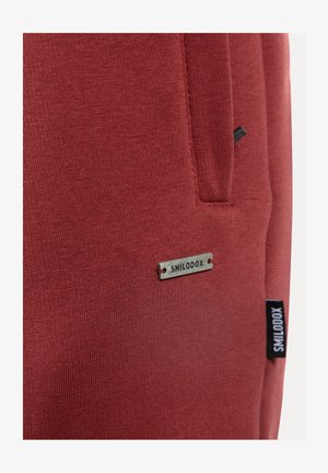 Rode sweatshirt met een zachte textuur, voorzien van een zilveren "SMILODOX"-label en een zwart zijlabel. Heeft een opvallende zakdetail.