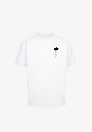 Biała bawełniana koszulka z małą czarną grafiką przedstawiającą postać trzymającą dwa czarne balony w kształcie serca na lewej stronie klatki piersiowej.