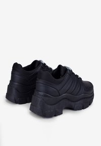 Sneaker chunky neri con un superiore sintetico liscio, dettagli testurizzati e suole in gomma spessa con un design a strati e linee audaci.