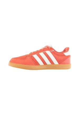 Zapatillas de ante rojo con rayas blancas, suela de goma y forro textil. Presentan una puntera suave y detalles perforados en los laterales.