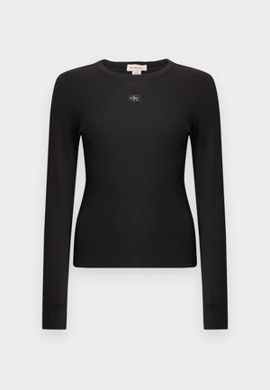 Sort langærmet ribbet top med rund hals og et lille CK-logo i midten. Har en tætsiddende pasform og blød tekstur.