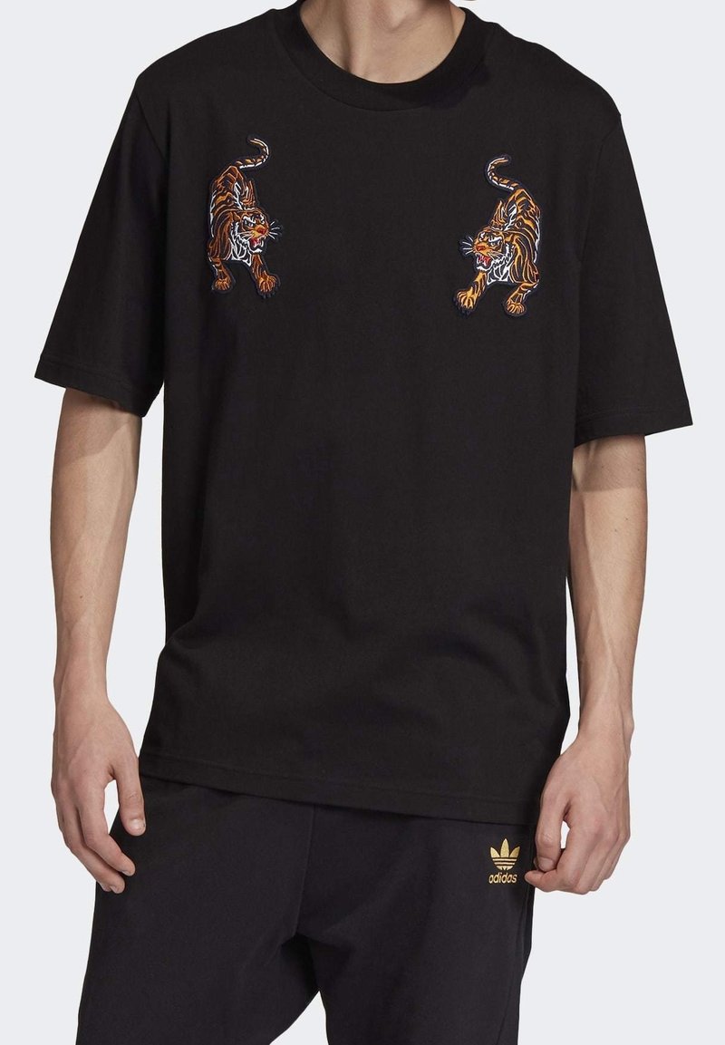 Svart bomullströja med rund hals, med två broderade tigrar i orange och vitt på framsidan. Lätt och ledig passform med korta ärmar.