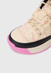 Fette Sneakers mit cremefarbenem Obermaterial aus Stoff, das pinke abstrakte Muster aufweist, schwarzer Lederkappe, cremefarbenen und schwarzen Schnürsenkeln sowie einer pinken Gummisohle.