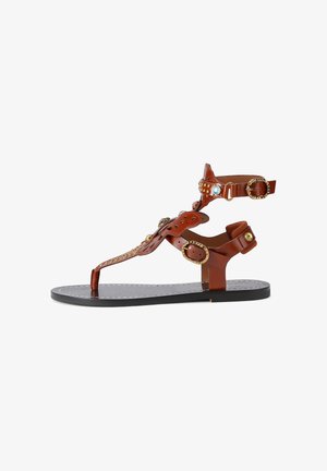 Sandalo piatto marrone con cinturini alla caviglia e alle dita, fibbie dorate e borchie decorative blu e dorate sulle fasce superiori in pelle.