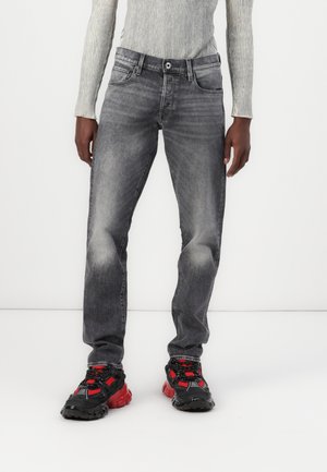 Grå denimjeans med rett benkutt, med en falmet finish og fem lommer. Kombinert med robuste svarte og røde sneakers.