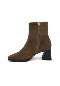 Botín de ante marrón hasta el tobillo con punta afilada, cremallera lateral y tacón grueso. Textura suave con un diseño sencillo, sin adornos adicionales.