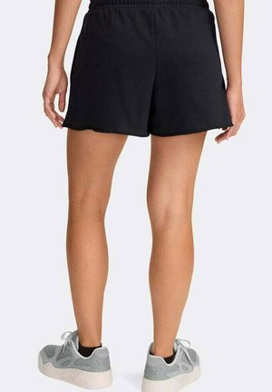 Shorts de sport noirs avec une taille élastique, dotés d'une coupe ample. Portés avec des baskets grises à design texturé.