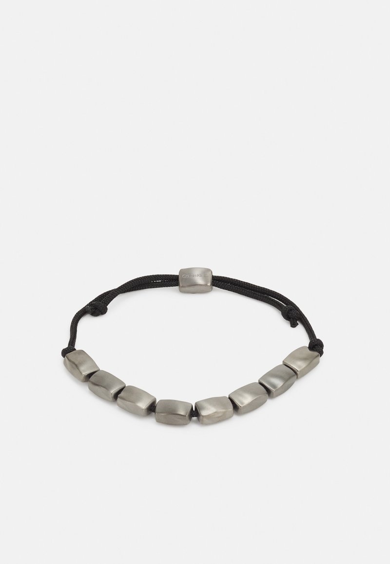 Musthave mustra kaablik, millel on must reguleeritav nöör ja halli metalli ristkülikukujulised helmed, mis on ühtlaselt jaotatud nööri ulatuses, keskel asub klambri tähistav helmes.