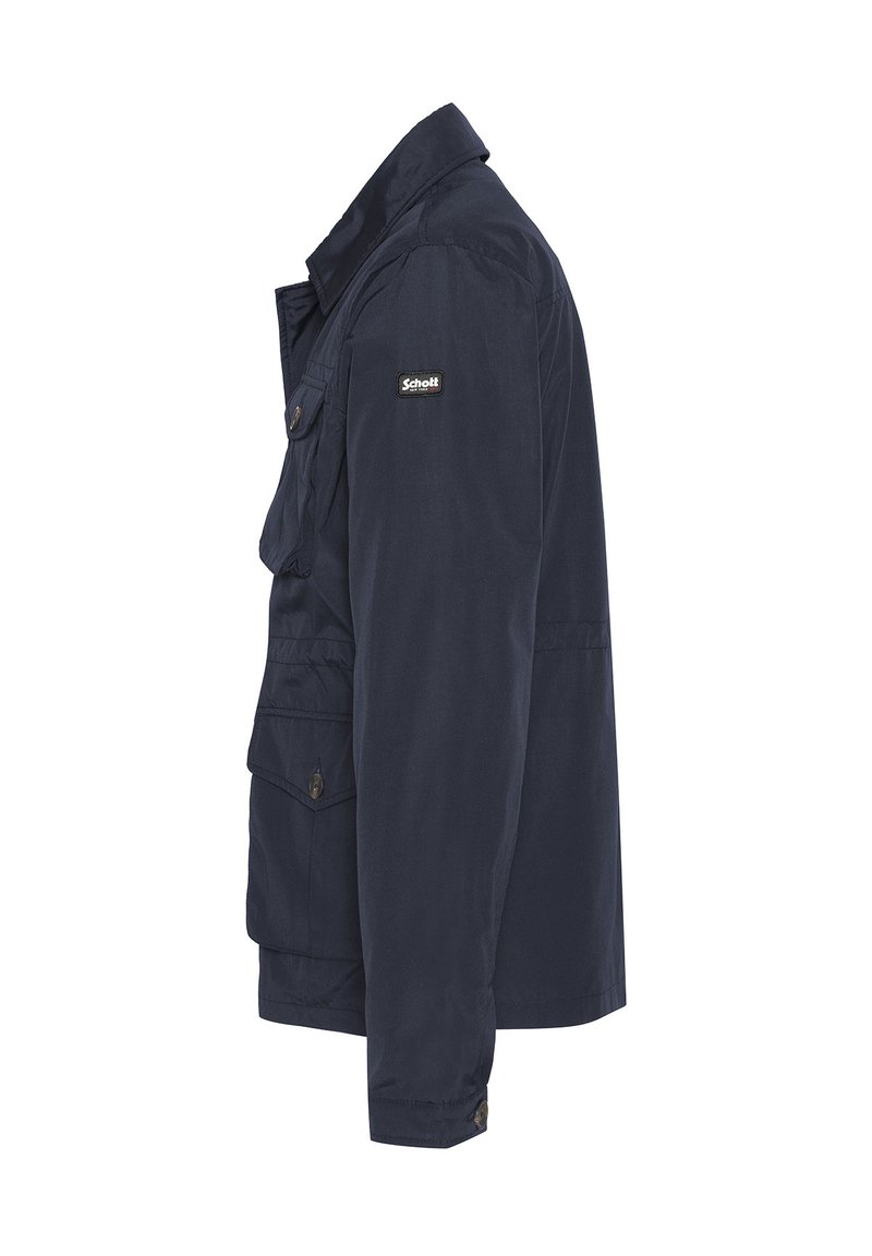 Giacca blu navy con un colletto, diverse tasche e una texture di tessuto. Presenta un patch con logo sulla spalla sinistra.