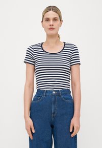 Striped t-shirt in navy and white, featuring a rounded neckline and short sleeves, paired with high-waisted blue denim jeans.