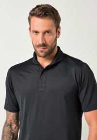 Polo nero realizzato in tessuto liscio, con colletto e apertura a tre bottoni, maniche corte e vestibilità moderna.