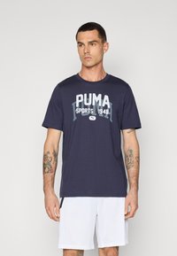 Marineblauwe katoenen T-shirt met korte mouwen, voorzien van het PUMA-logo en de tekst "Sports 1948" in wit en lichtblauw. Klassiek ontwerp met ronde hals.