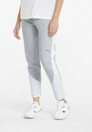 Person wearing grey and white Puma leggings and white Puma sneakers, standing against a plain white background.