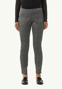 Czarno-białe spodnie w kratę o dopasowanym kroju, gładkiej strukturze, płaskim przodzie i zwężanych nogawkach, w połączeniu z błyszczącymi czarnymi mokasynami.