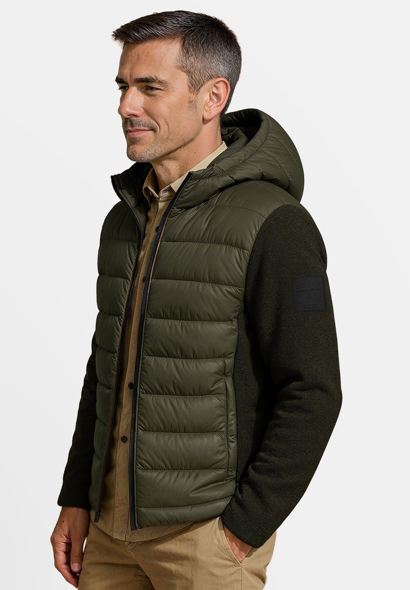 Opgevulde olijfgroene gilet met een capuchon, voorzien van een donkergroene wolmix op de mouwen en een ritsluiting. Textuur en geïsoleerd ontwerp.