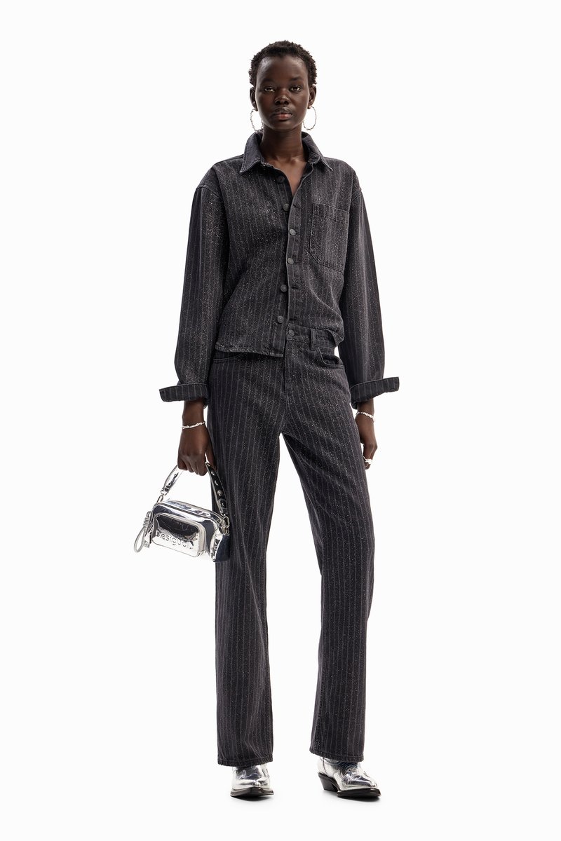 Black pinstriped denim jacket and pants, paired with a silver handbag. The outfit has a relaxed fit with a textured appearance and metallic accents.