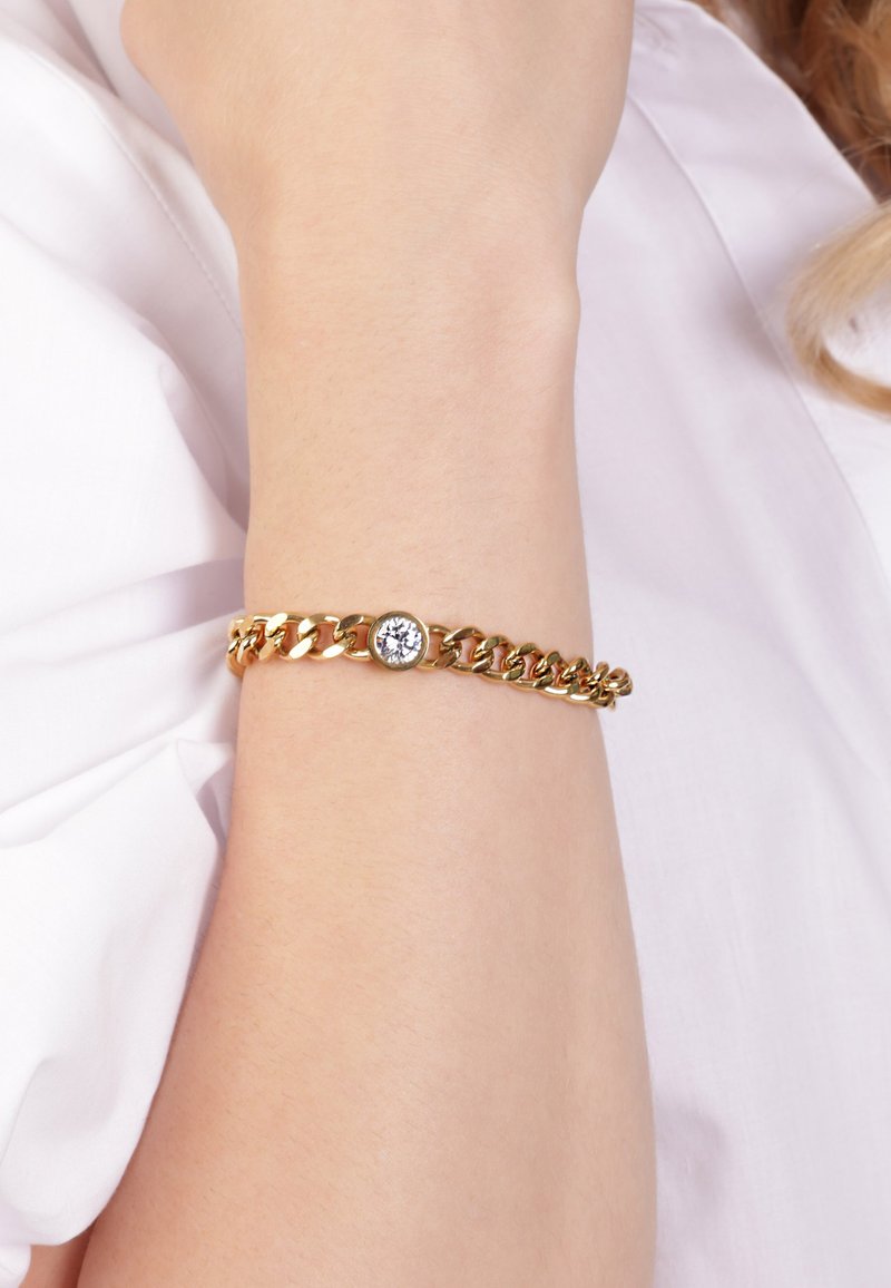 Gold chain bracelet featuring a round clear gemstone accent, with interlocking links and a smooth finish, worn on the wrist.