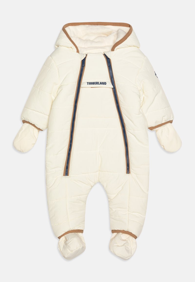 Combinaison blanche en duvet avec capuche, fermeture éclair et accents bruns. Comprend des mitaines et des chaussons intégrés pour une couverture complète.