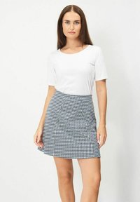 Svart- och vitrutigt tygkjol med utsvängd design, tillverkad av lättviktig tyg. Kombinerad med en enfärgad vit t-shirt med kort ärm.