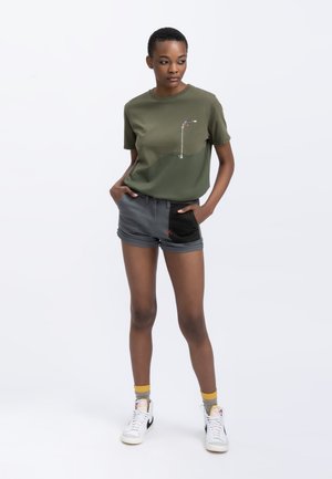 Khaki groene t-shirt met een gradient ontwerp en grafische print, gecombineerd met grijze shorts met een zwart accent en rode stiksels.